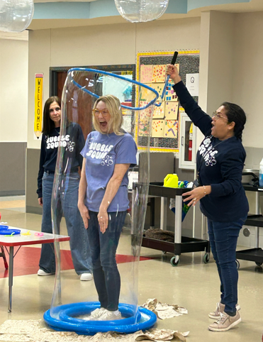 Mrs. Lindsay is inside a big bubble wand to show students that bubbles have air.