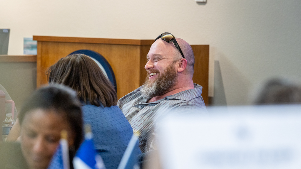 male teacher at table smiling broadly