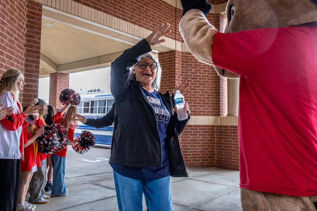 female guest smiling and raising hand to high five Minshew mascot