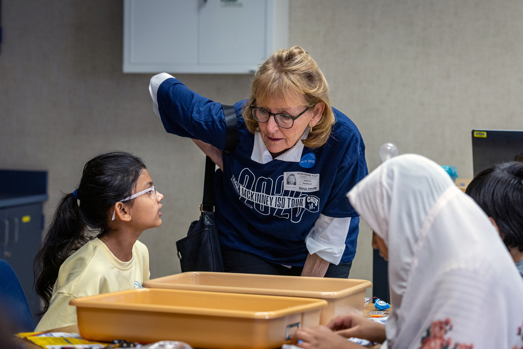 guest at Minshew leaning in and talking to a female student working at her desk