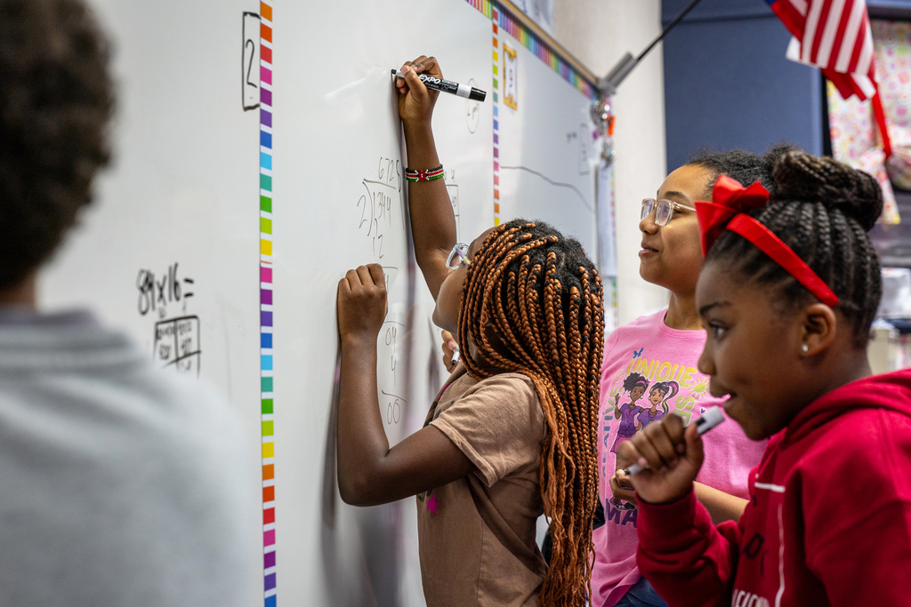 female students working on math problems on the whiteboard