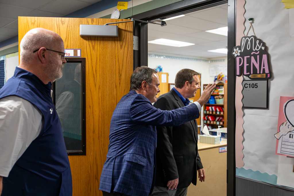 Cox leaning into classroom waving