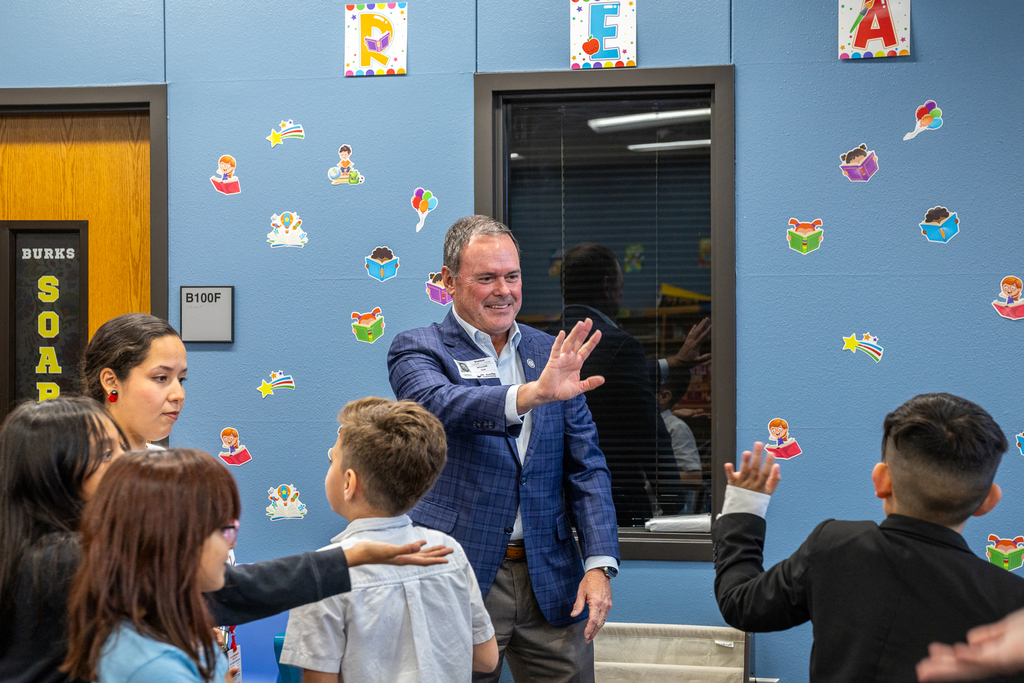 Cox smiling and waving to student who is waving at him