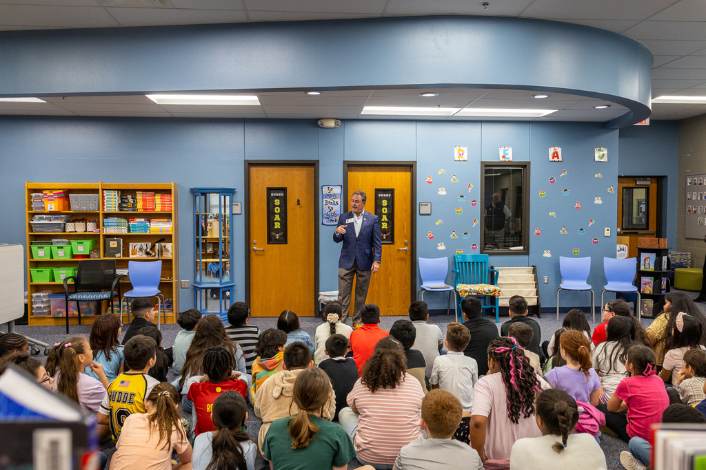 Cox standing in front of group seated on floor in the library