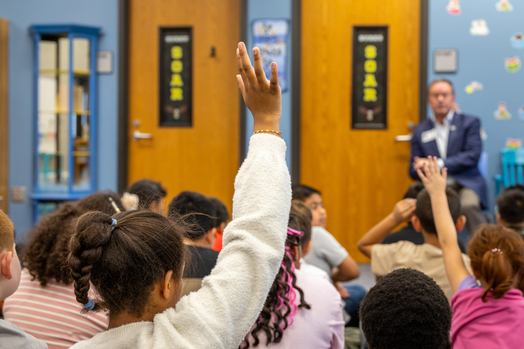girl in foreground with hand raised 
