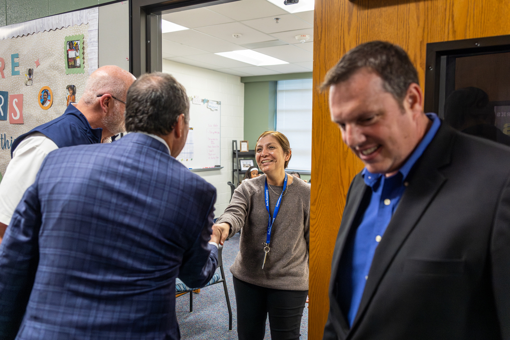 Teacher shaking hands with Cox at classroom door