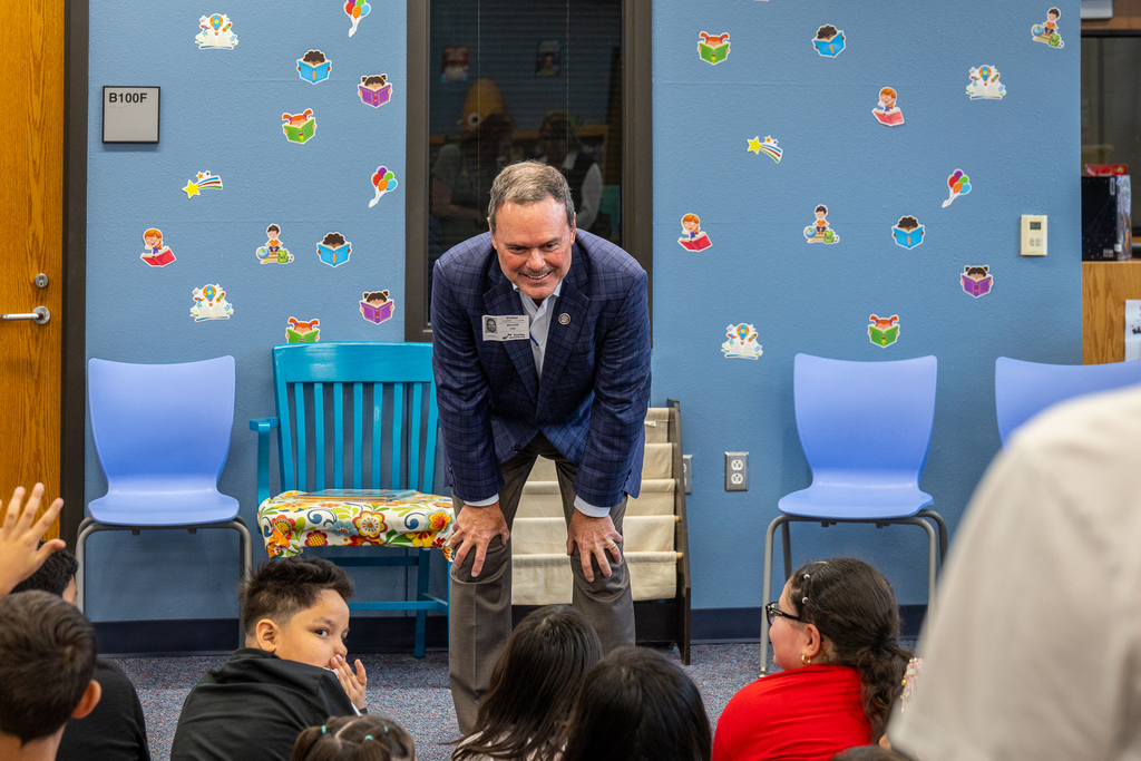 Cox leaning forward listening to student and smiling