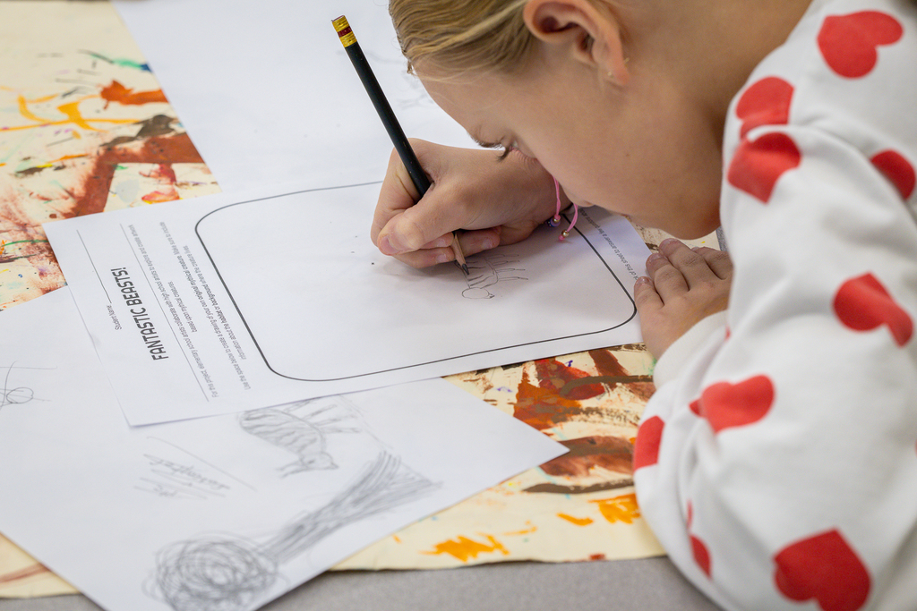 3rd grade female at desk in class working on initial concept sketch for project