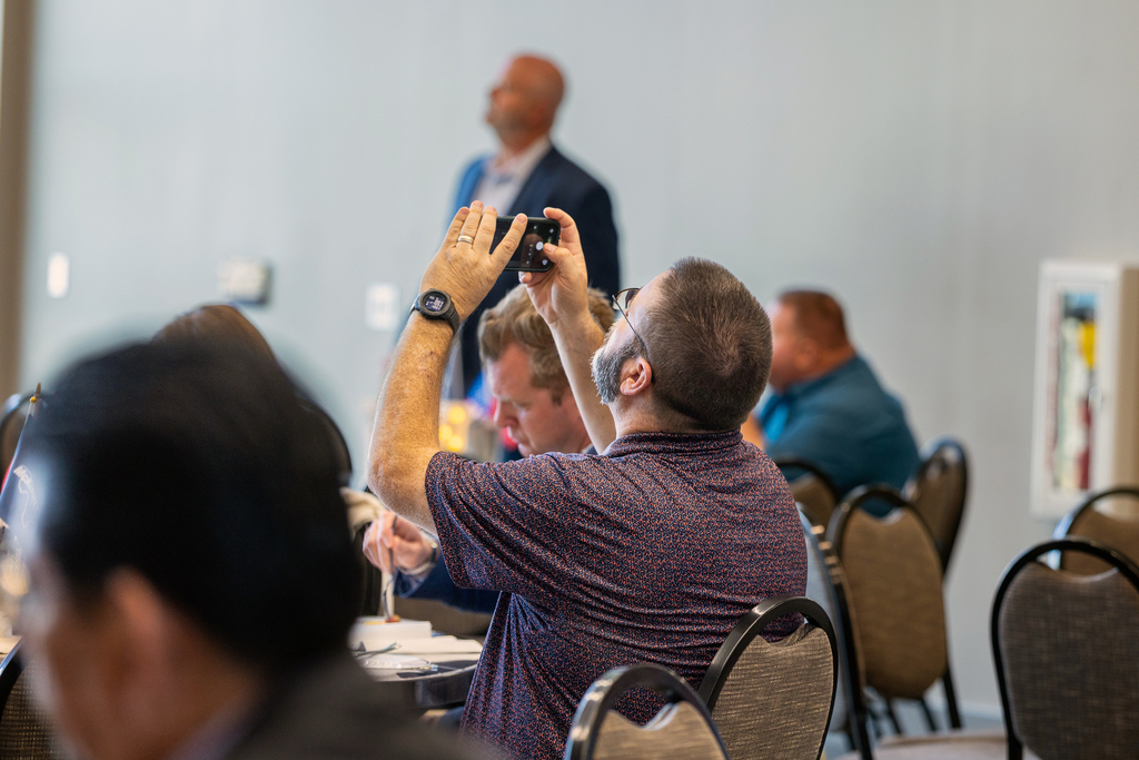 man holding up phone to take photo of screen