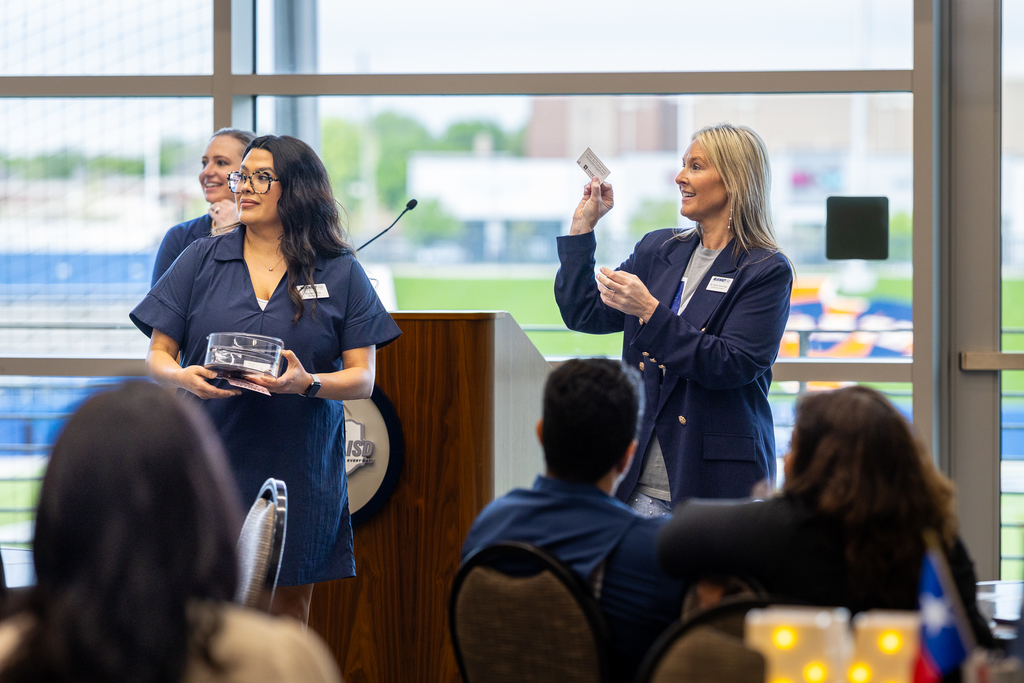 Spaulding holding up a business card at front of room