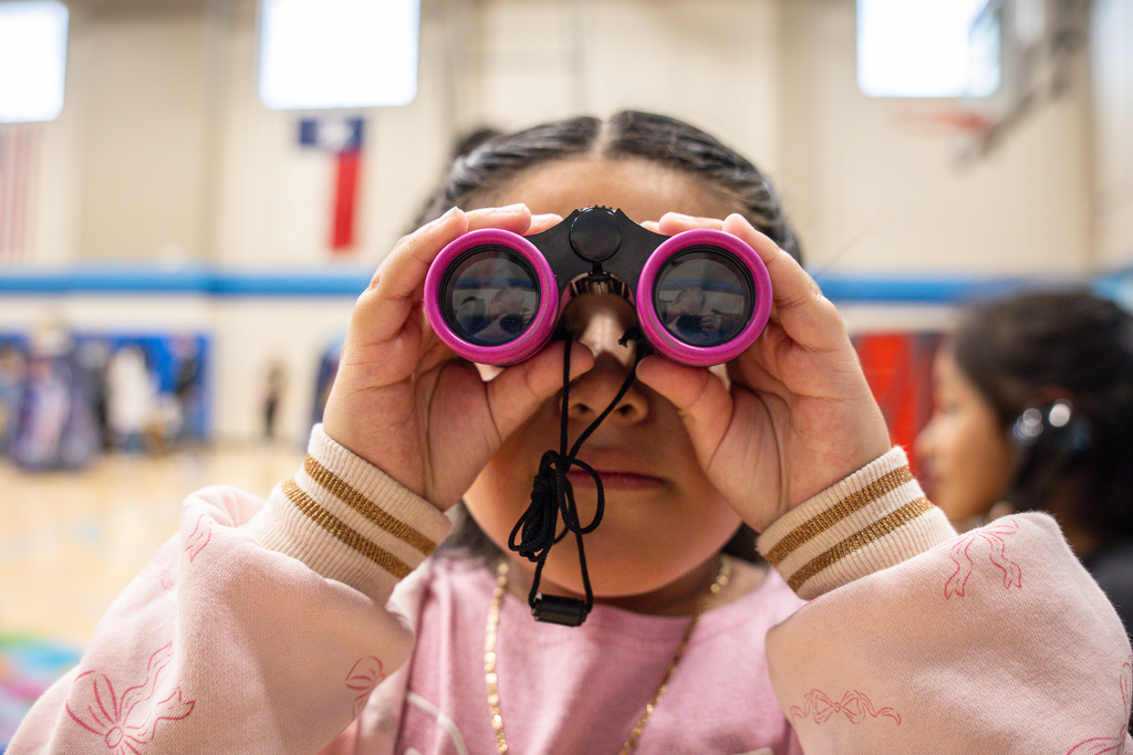 girl looking at camera through binoculars