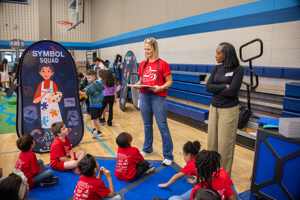 teacher standing in front of group seated on floor giving them instructions