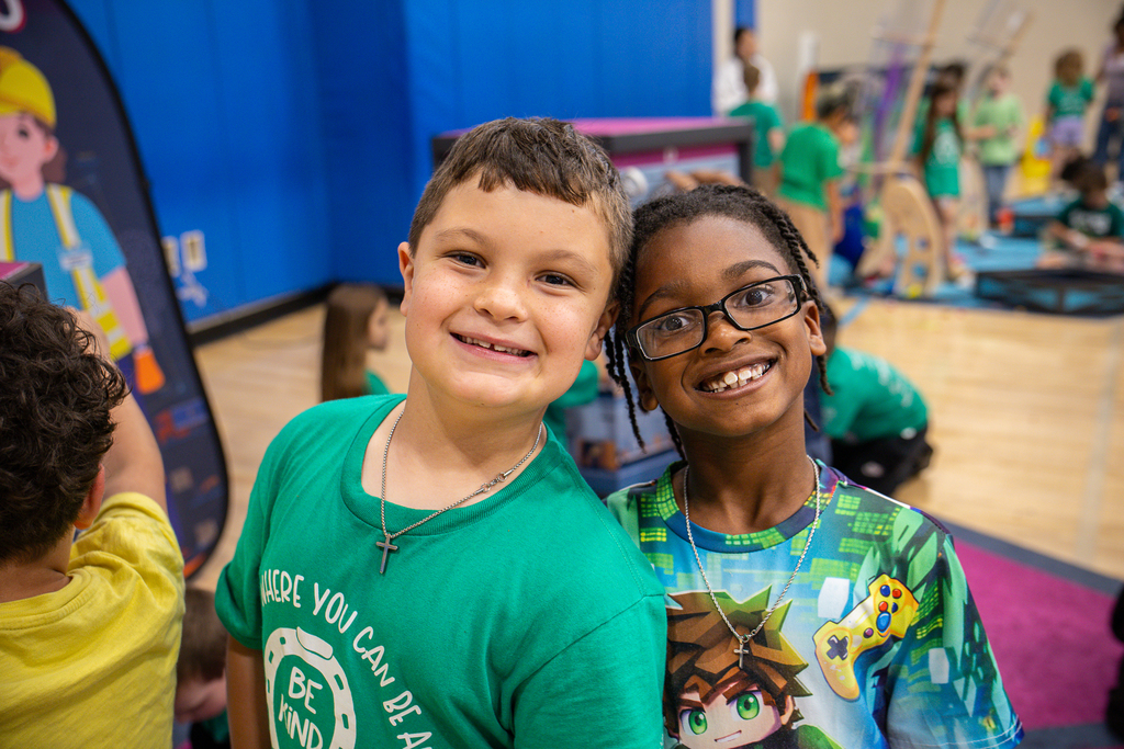 two boys leaning together and smiling at the camera