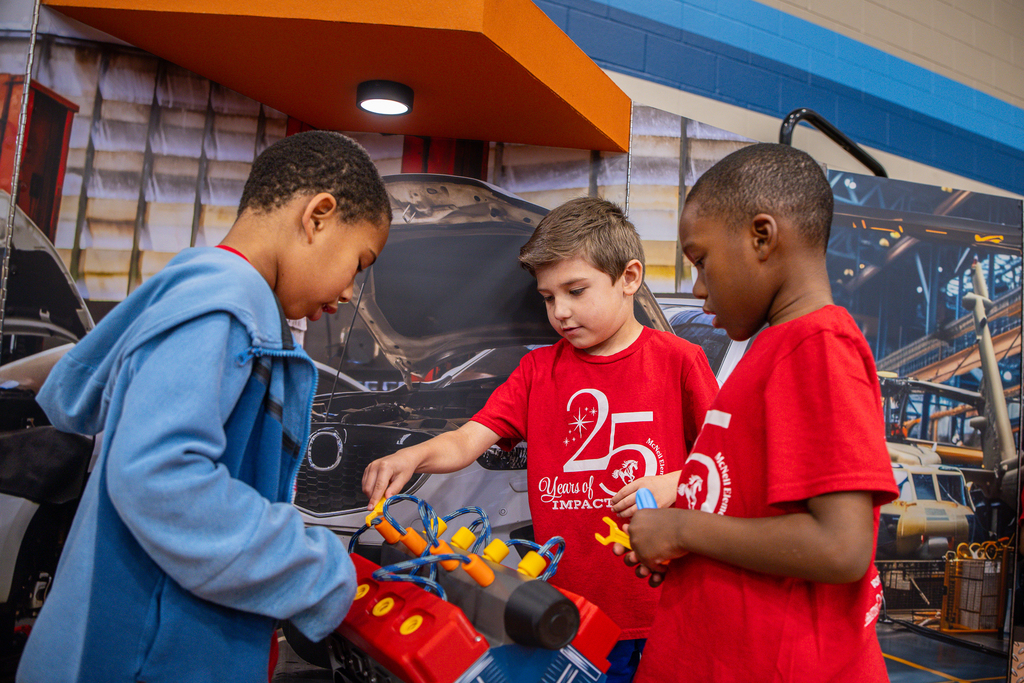 three boys playing with toy engine block replica