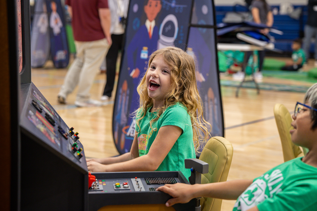 girl laughing as she plays on a toy helicopter cockpit