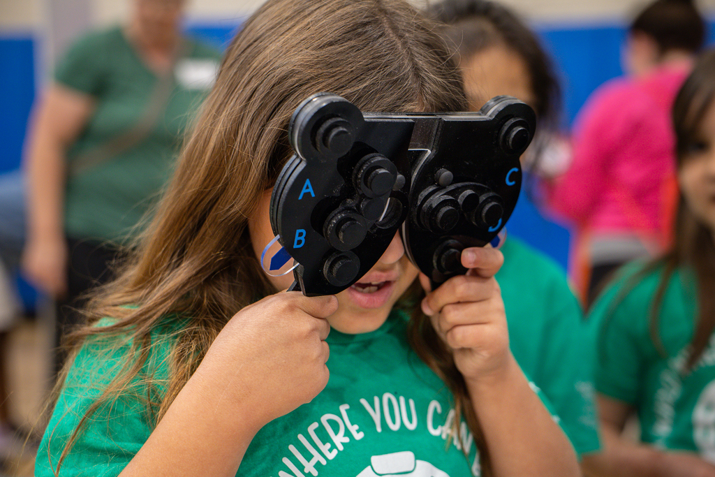 girl playing with optometrist equipment held up to her eyes