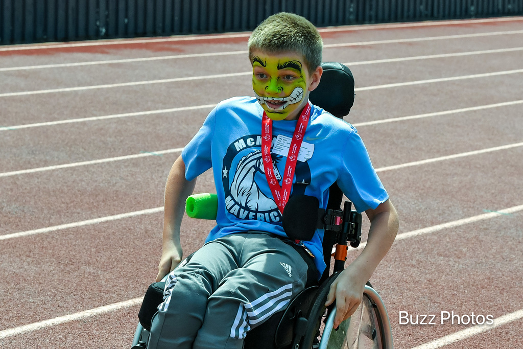 male competitor on track in wheelchair with green facepaint