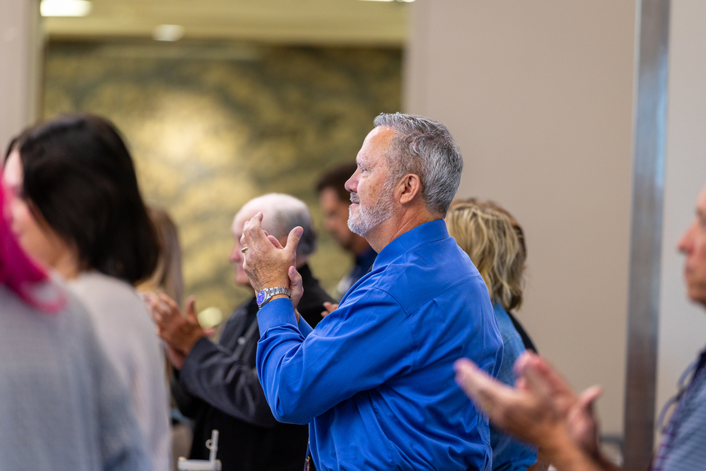 man standing and smiling while clapping