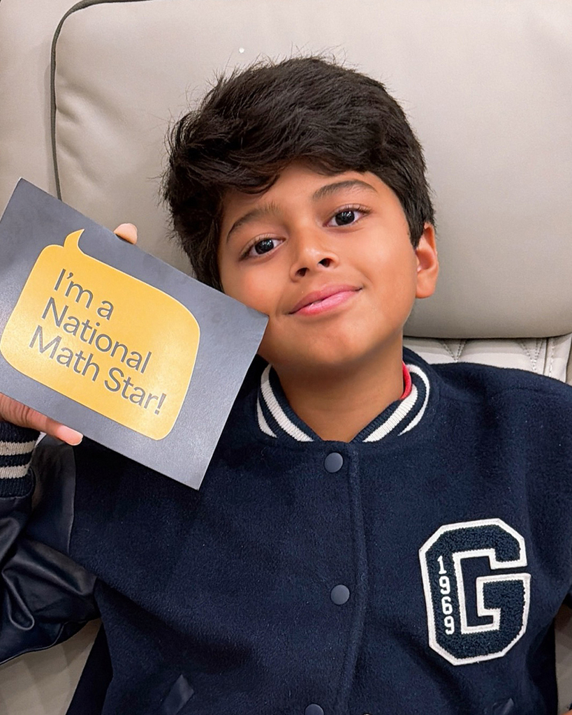 Kiaan smiling and holding an "I'm a National Math Star!" card