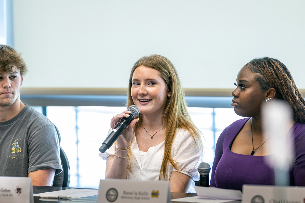 girl smiling with microphone and speaking during panel discussion