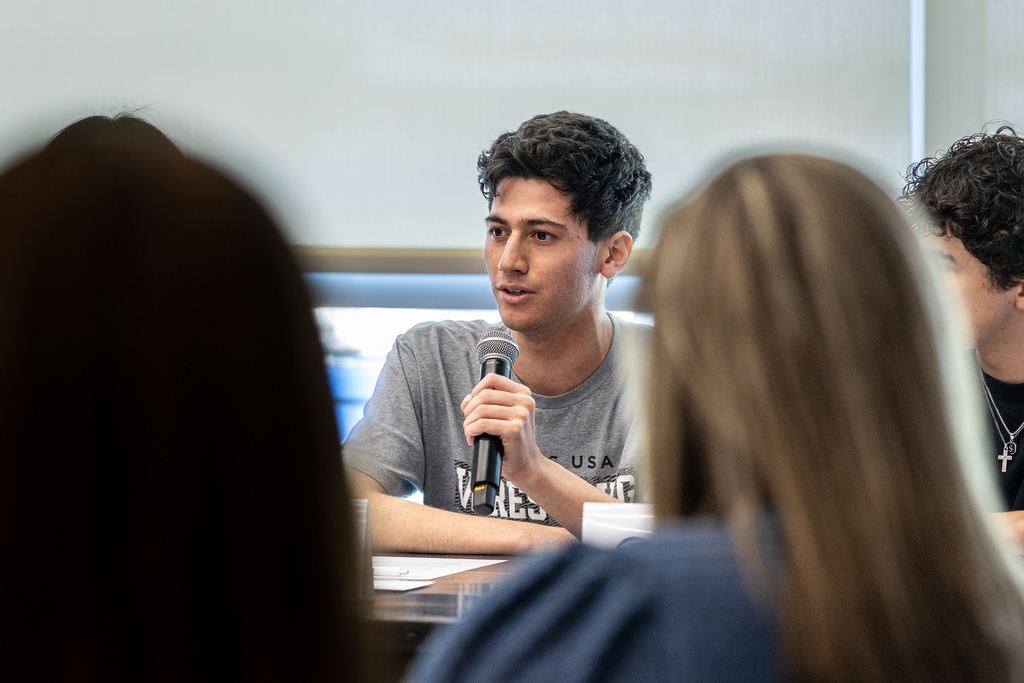 male student speaking with microphone during panel