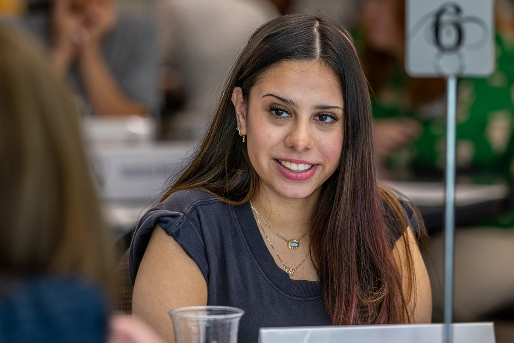 girl smiling and listening to principal during group activity at table