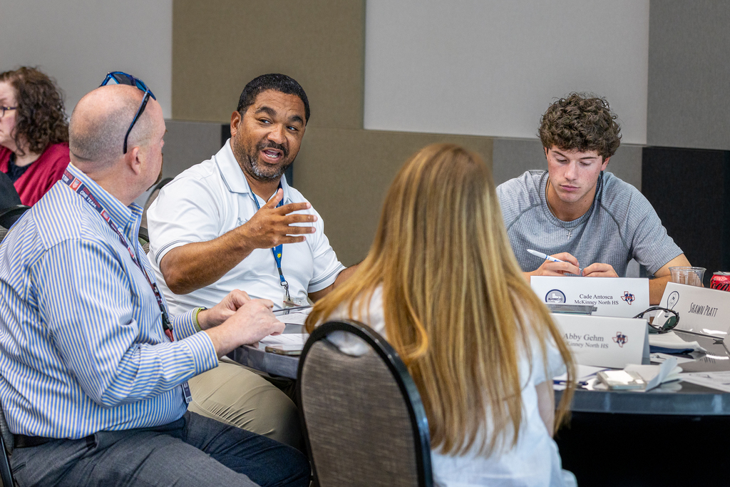 teachers and students talking at table during group activity