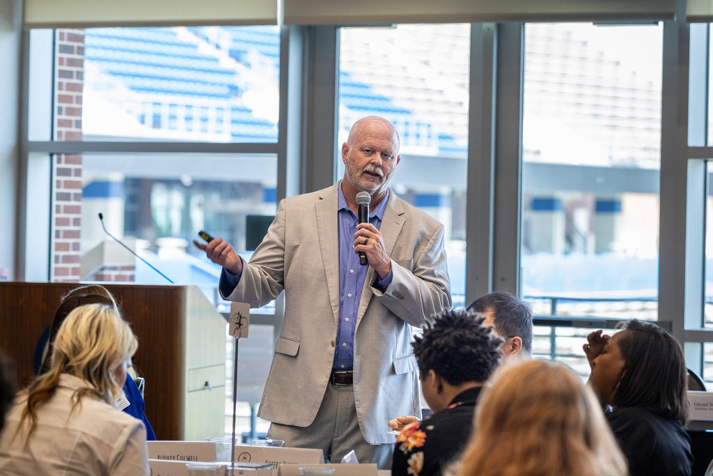 Pratt speaking with microphone to group