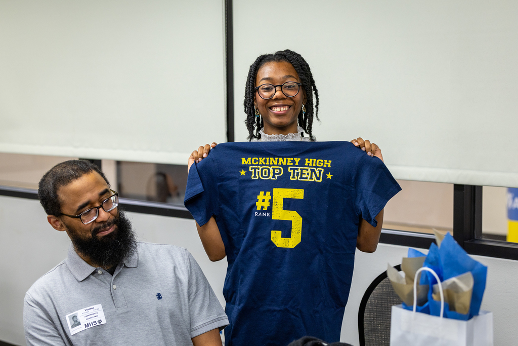 #5 student Zalana Aguillard holding up #5 shirt and smiling