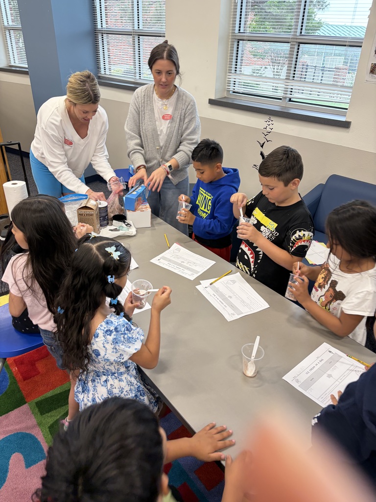 Volunteers guide 2nd graders through a science experiament.