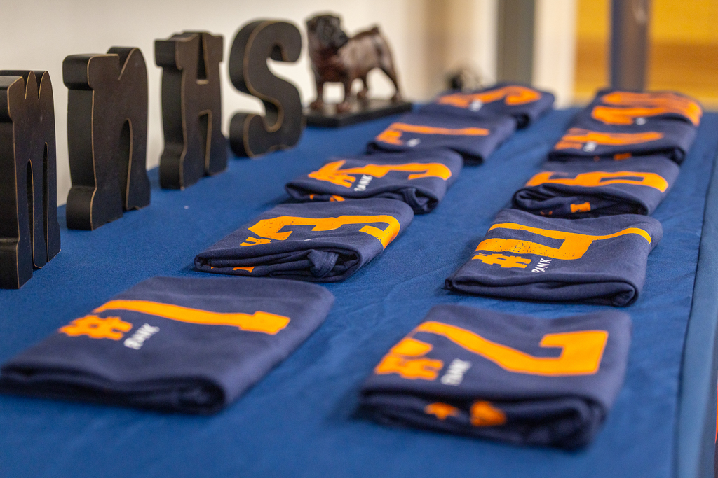 folded shirts with ranks on them sitting on front table