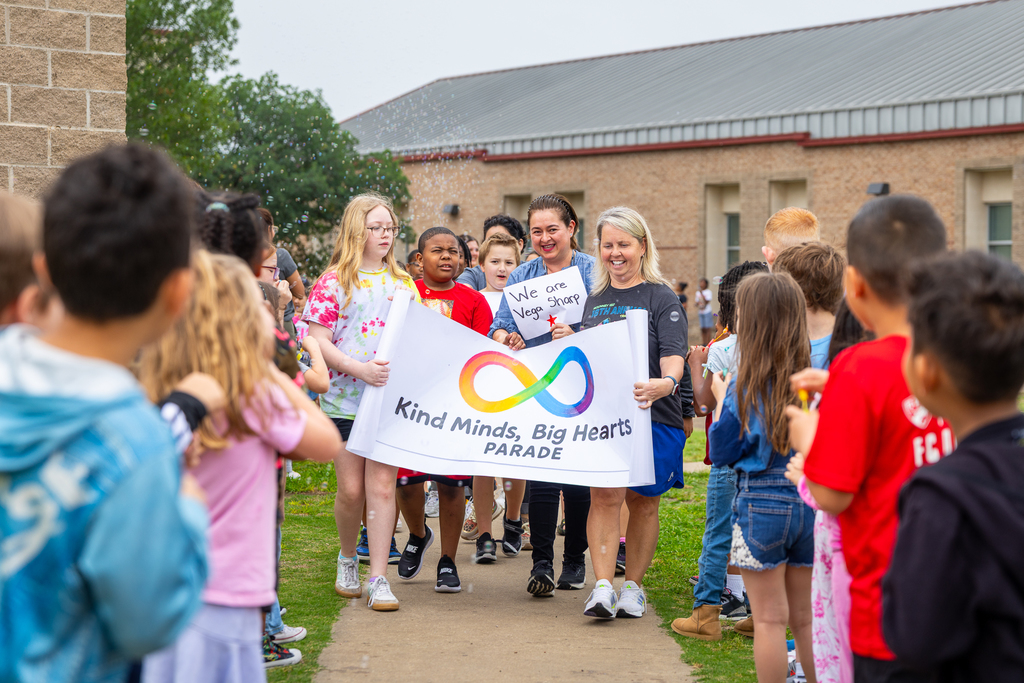 teachers and special needs students with general education friends walking toward students who are lining the side walk to blow bubbles