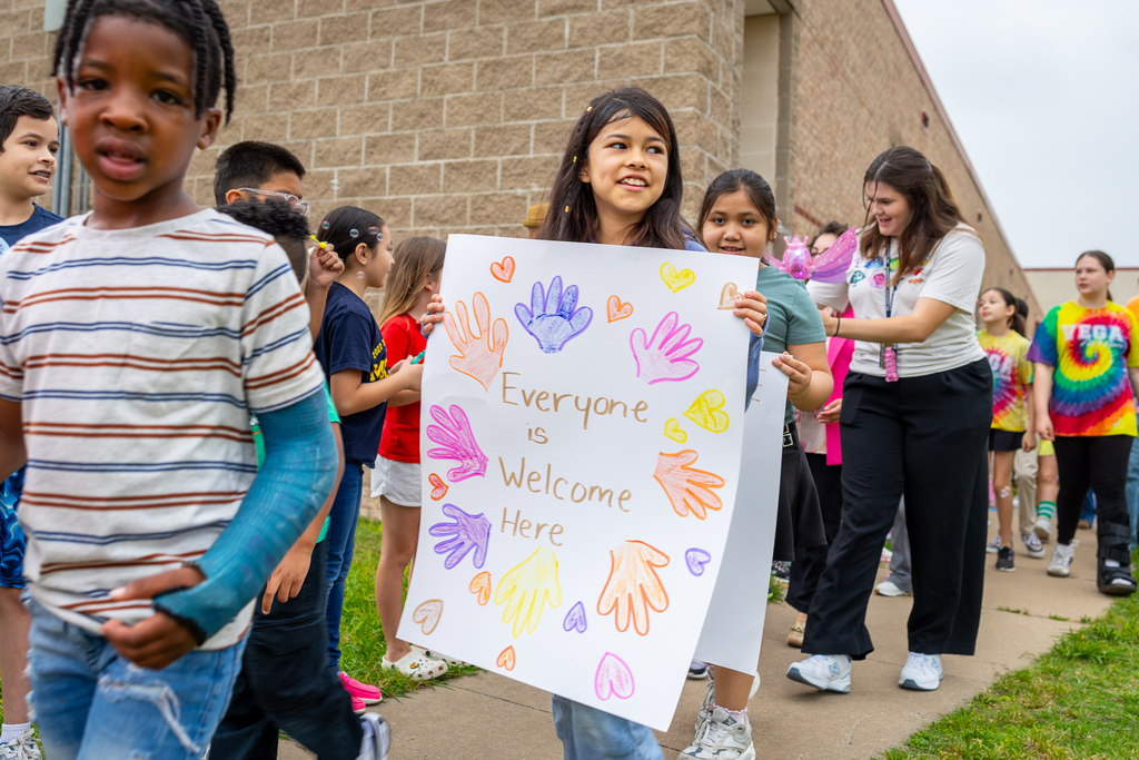 Girl walking with sign that reads "Everyone is welcome here."