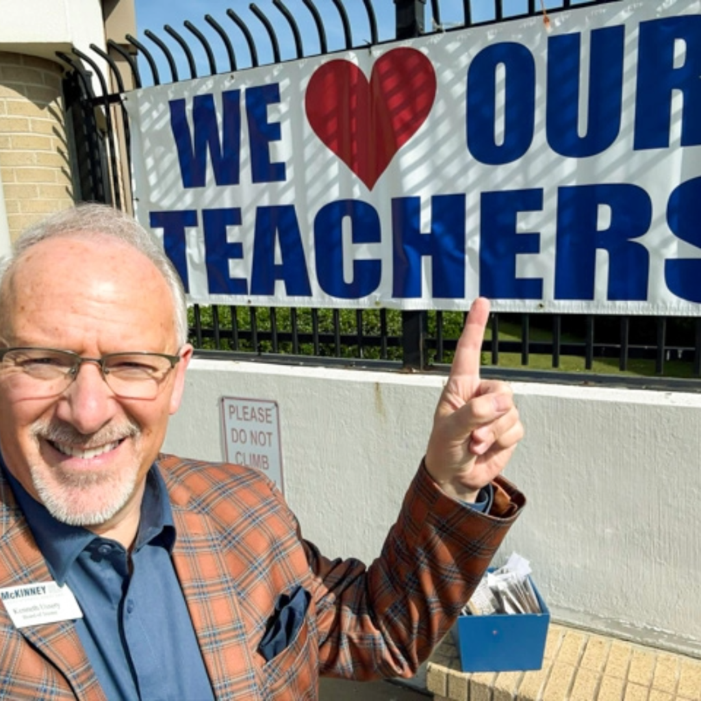 board member kenneth ussery points to a we love our teachers sign