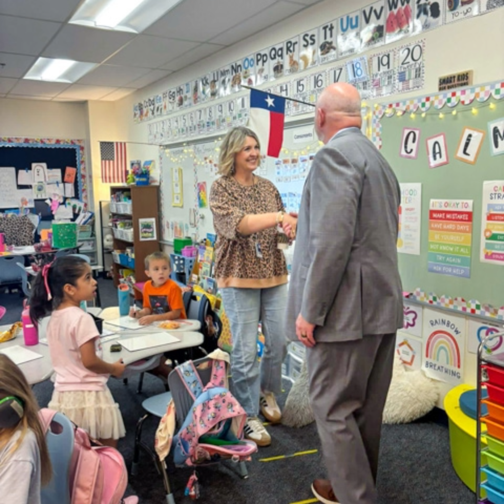 superintendent shawn pratt shakes hands with reuben johnson teacher lisa strealy 