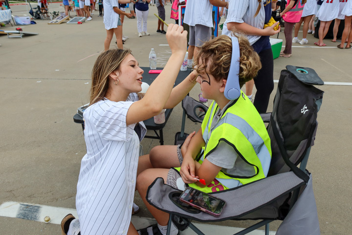 a student is painting the face of another student 