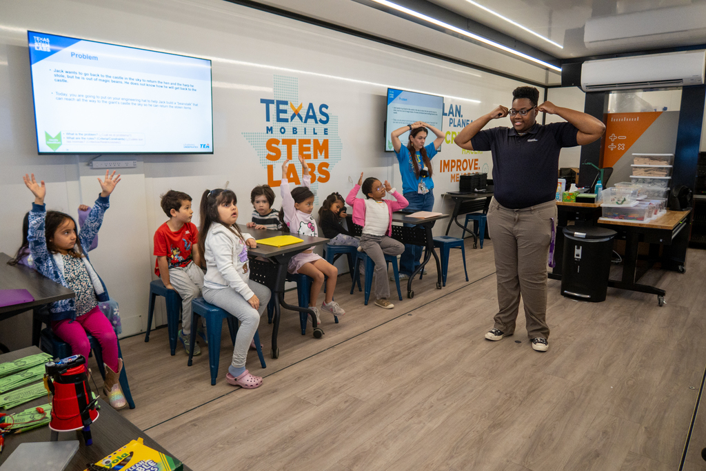 students sit and listen to the mobile stem lab teacher 
