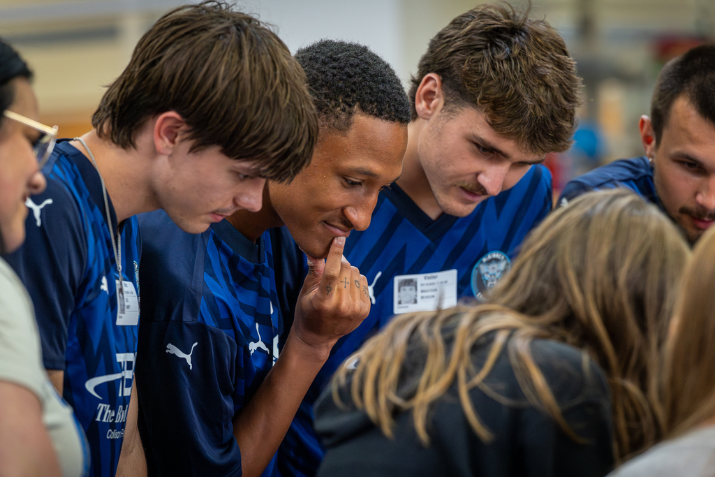 players leaning in and looking at project with students