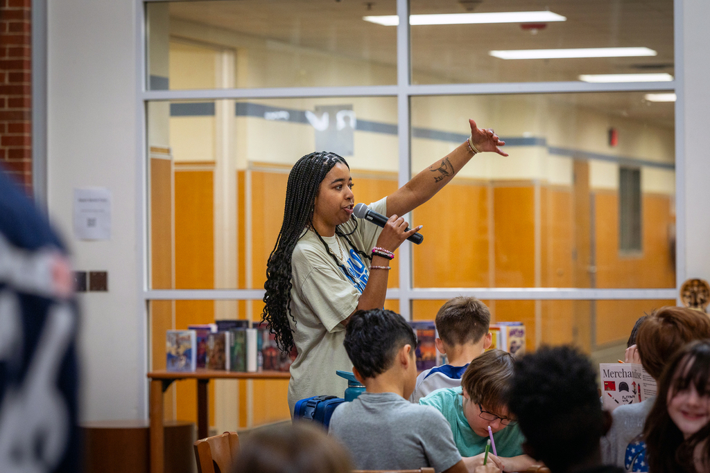 teacher speaking on microphone and gesturing with hand