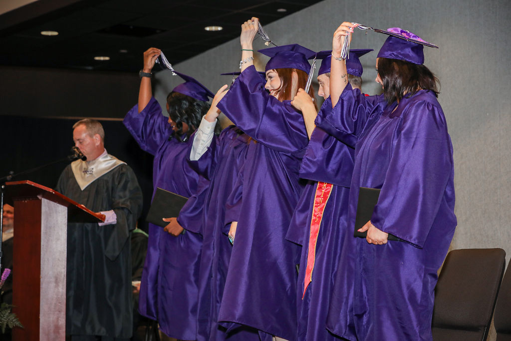 graduates onstage turning tassels