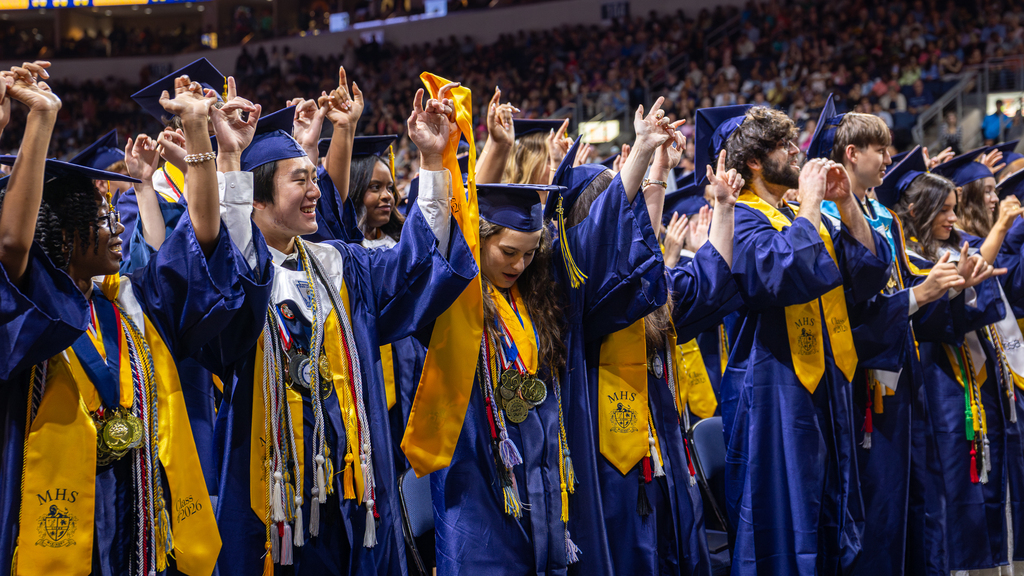 graduates in the front row lifting hands together during school song