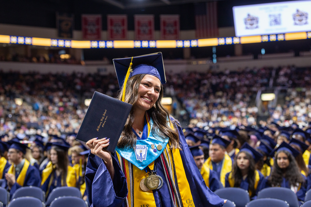 female graduate holding up her diploma for photo