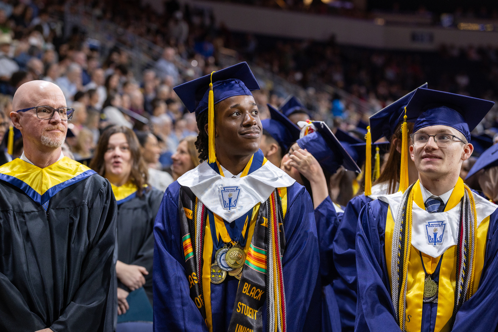 graduate in front row looking up toward the video board