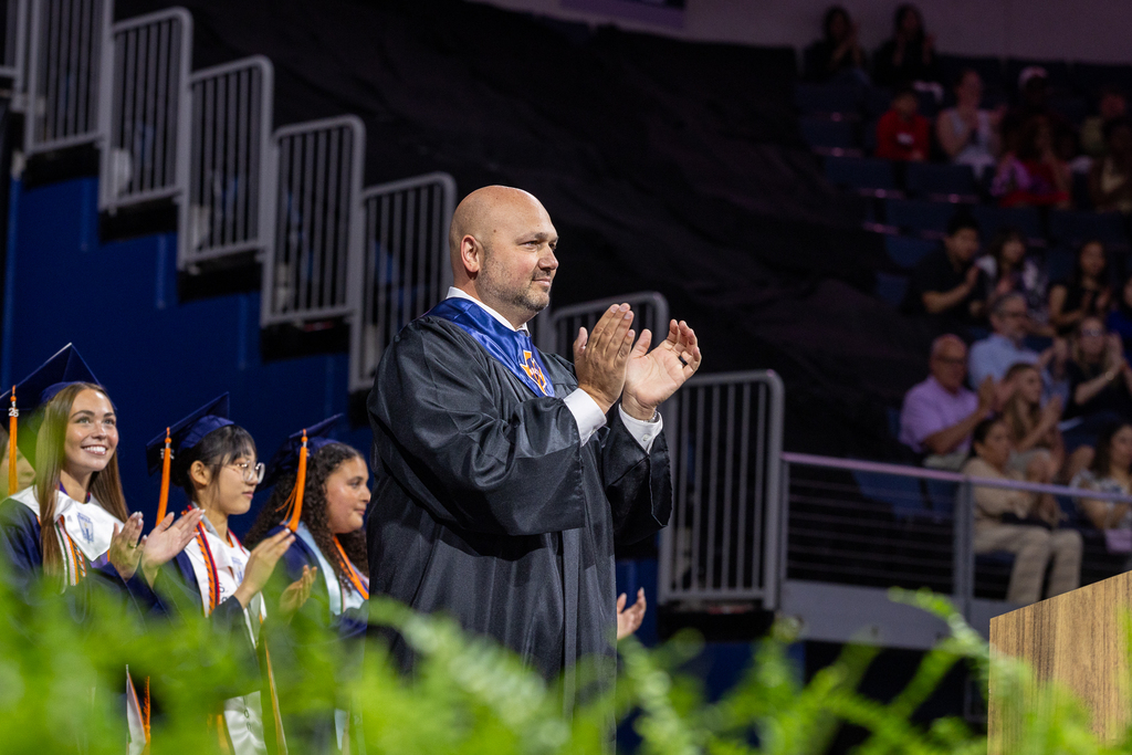 principal Justin Penio clapping onstage