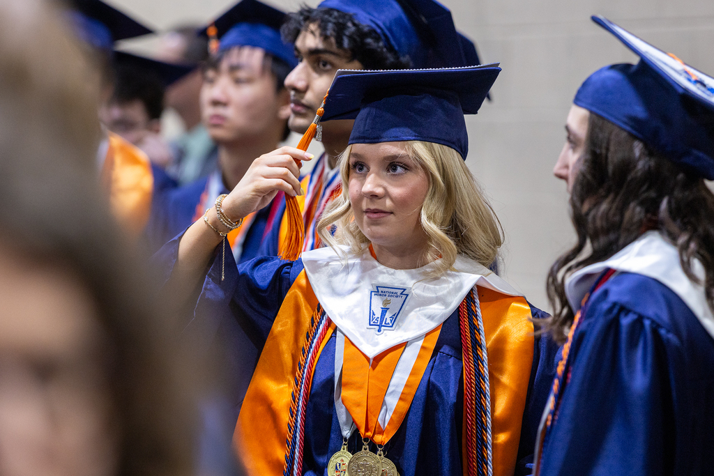 female graduate holding and looking intently at her cap tassel
