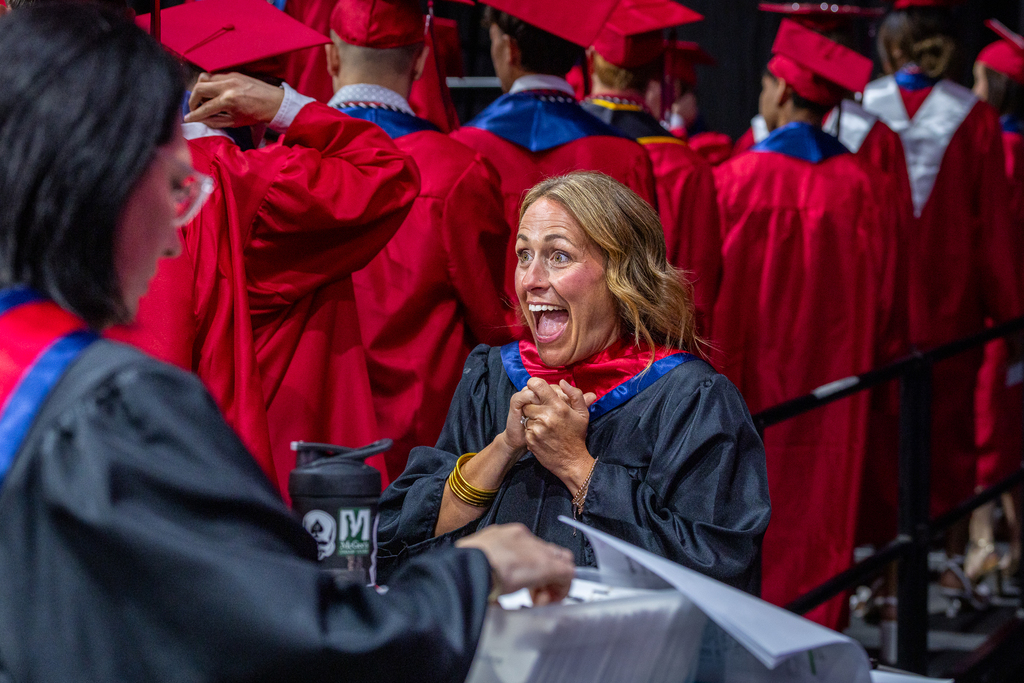 teacher reacting with excitement to seeing graduate