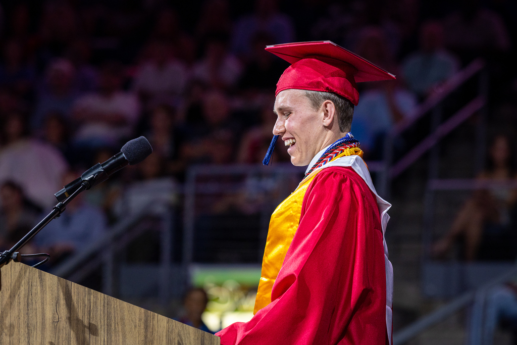 male graduate at the podium laughing