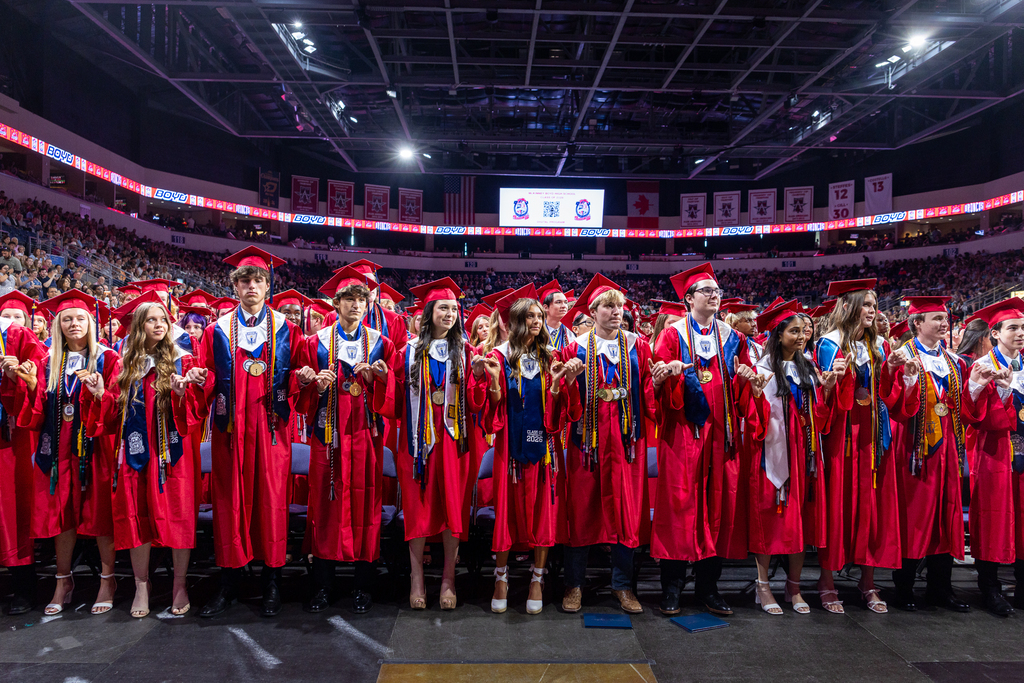 front row of graduates standing for the school song