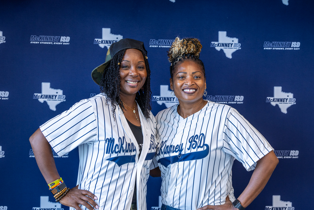 two attendees smiling in front of photo backdrop