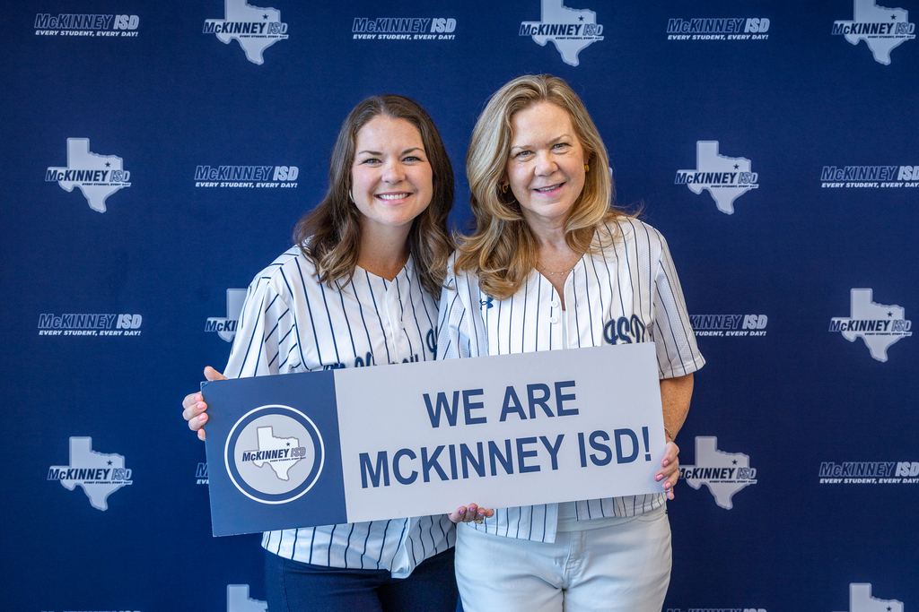 mother and daughter administrators in front of photo backdrop with we are mckinney isd sign